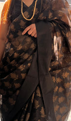 Woman wearing a black and gold handloom saree with geometric patterns, accessorized with a bead necklace