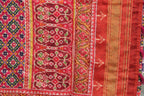 Traditional red bandhani fabric with intricate geometric and floral patterns, hand-embroidered details