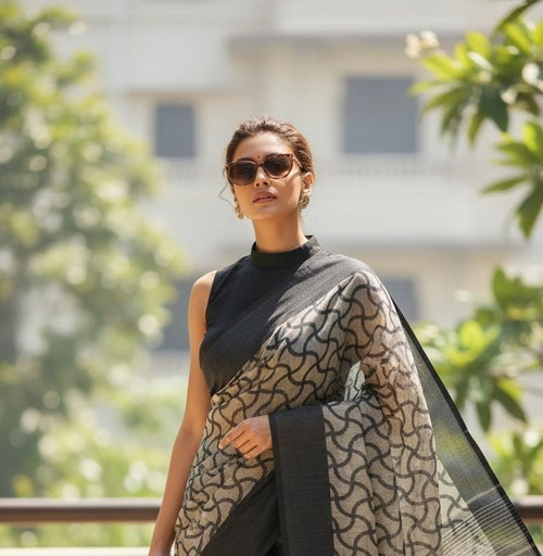 Woman wearing off-white and black printed saree with sunglasses, outdoor setting