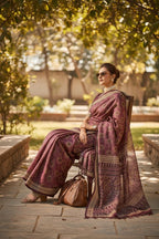 Woman in elegant maroon patterned saree with sunglasses, sitting outdoors in sunlight