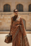 Woman in brown printed saree with sunglasses carrying leather handbag outdoors