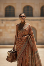 Woman in brown printed saree with sunglasses carrying leather handbag outdoors