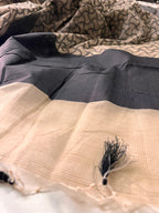 Elegant beige and black saree with geometric pattern and tassel detail, close-up fabric texture