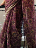 Woman wearing maroon saree with golden floral print and embroidered border